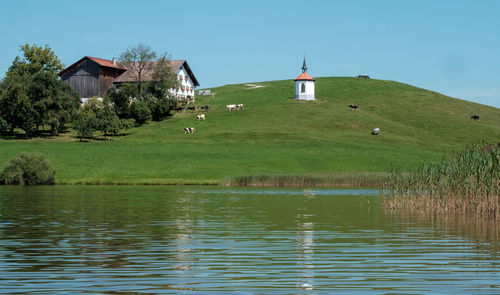 German farm house by lake against blue sky