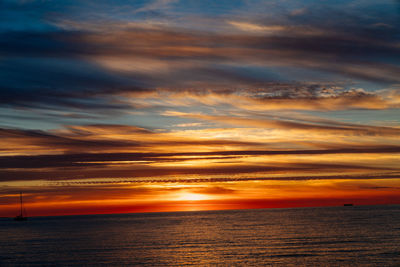 Scenic view of sea against dramatic sky during sunset