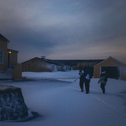 People walking on snow covered building against sky