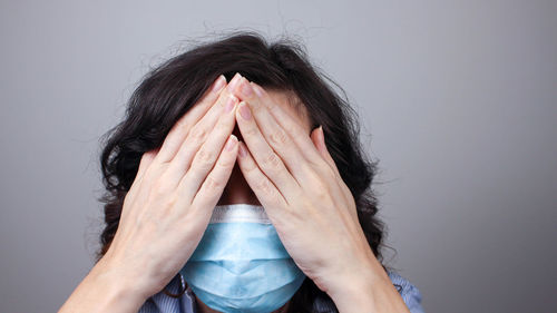 Portrait of person hiding covered with face against white background