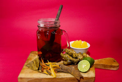 Close-up of drink in glass jar on table against red background