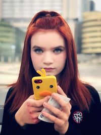 Close-up portrait of young woman with mobile phone