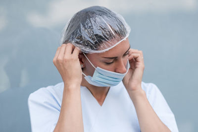 Portrait of a woman doctor putting on and fixing her surgical protective mask before her work shift