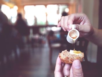 Cropped hand pouring honey on food