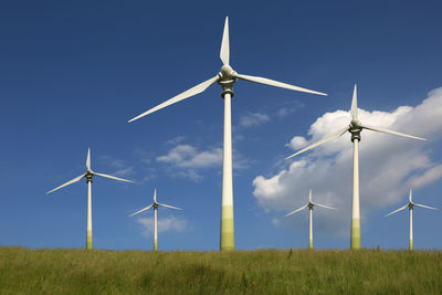 Wind turbines on field against sky