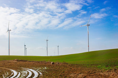 Scenic view of agricultural field against sky and wind turbines