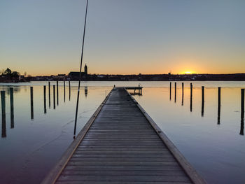 Pier over sea against clear sky during sunset