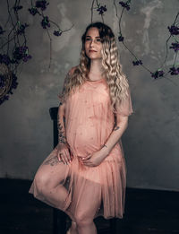 Portrait of woman standing against wall