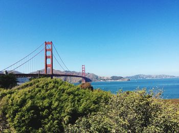 Suspension bridge over sea against blue sky