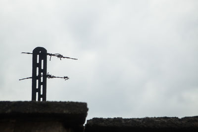 Low angle view of weather vane on field against sky