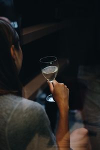 Close-up of woman holding wineglass seen through window