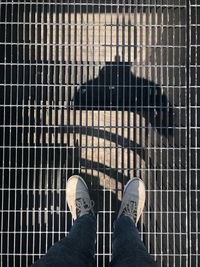 Low section of man standing on metal grate