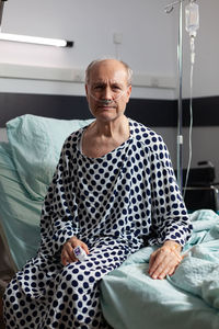 Portrait of man sitting on hospital bed