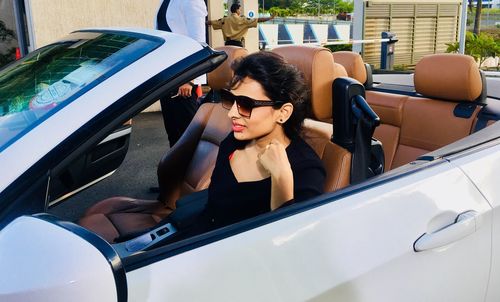 Woman wearing sunglasses while sitting in convertible car