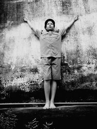 Low angle view of boy wearing police uniform while standing against weathered wall