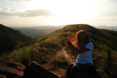 Woman taking pictures with smart phone on mountain