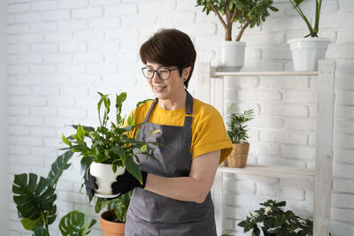 Side view of young woman standing against wall