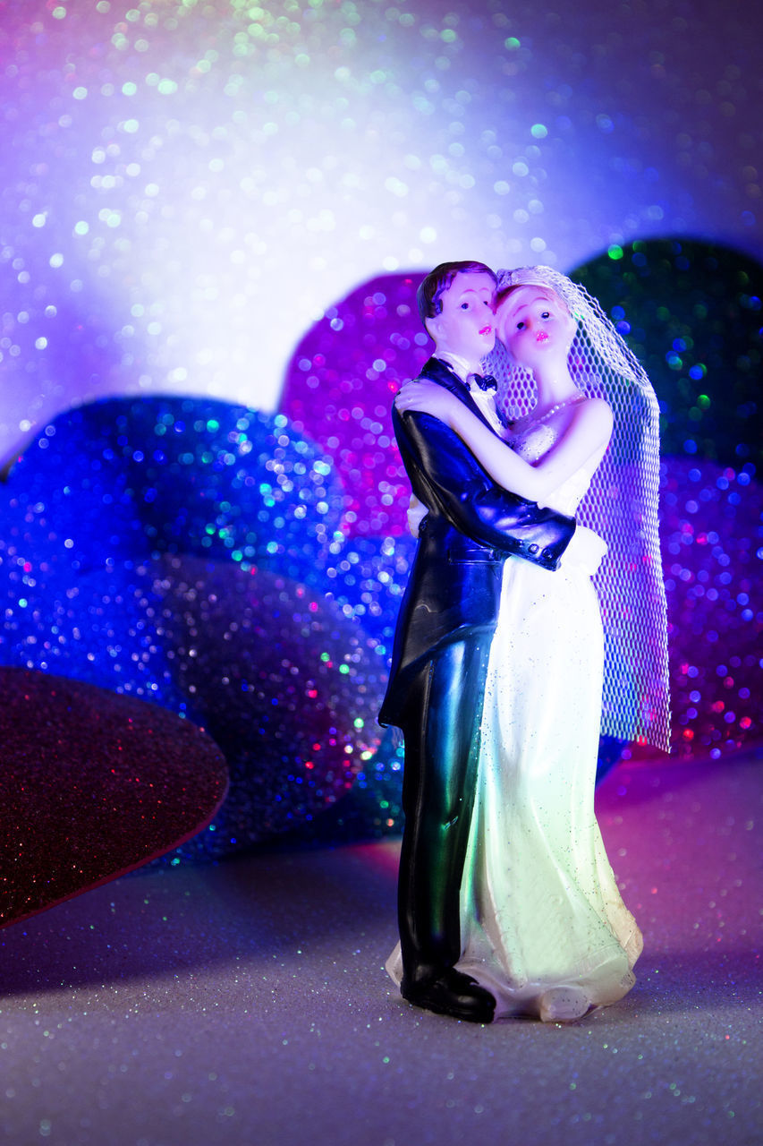 WOMAN STANDING AGAINST ILLUMINATED PURPLE WALL