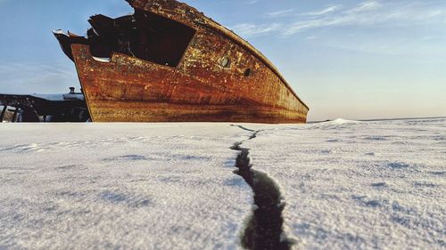 Old rusty bicycle on field against sky during winter