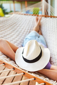 High angle view of man wearing hat relaxing on hammock
