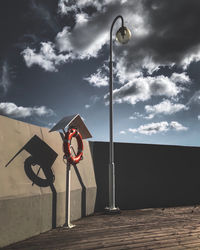 Road sign on street against sky