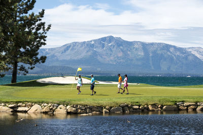 People enjoying at lake against sky