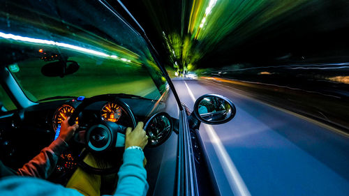 Blurred motion of man driving car on illuminated road