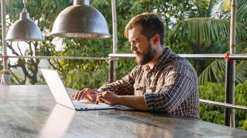 Young man using mobile phone while sitting on table