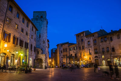 Illuminated city against clear blue sky at night