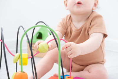 Portrait of cute baby boy with toy against white background