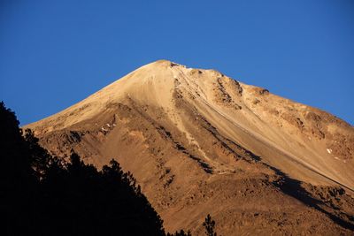 Low angle view of mountain against clear blue sky