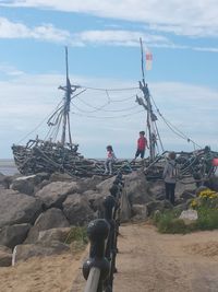 Rear view of people on rock by sea against sky