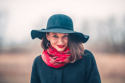 Portrait of woman wearing hat and red scarf against sky