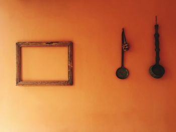 Empty picture frame and kitchen utensils on orange wall