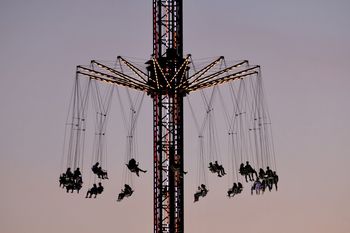 People on amusement park ride against clear sky