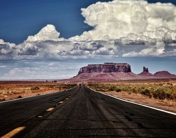 Road leading towards desert against sky