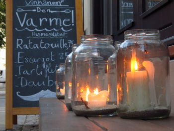Close-up of lit candles in glass