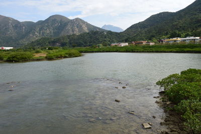 Scenic view of river by mountains against sky