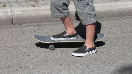 Side view low section of skateboarding on road