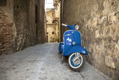 Bicycle parked on street against wall