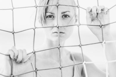 Close-up portrait of young woman seen through glass