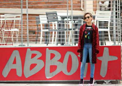 Portrait of woman standing against red brick wall