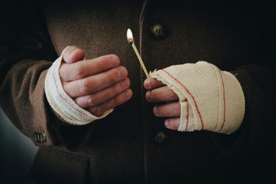 Midsection of man holding matchstick 