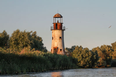 Lighthouse by lake against sky