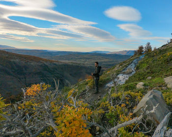 Rear view of man walking on mountain against sky