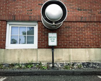 Close-up of road sign against brick wall