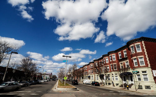 Cars on road by buildings against sky in city