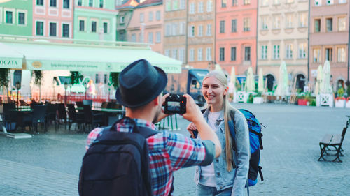 Side view of woman photographing on street in city