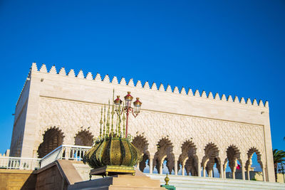 Low angle view of sculptures on building against blue sky