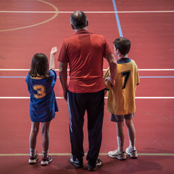 Rear view of father with children on basketball court